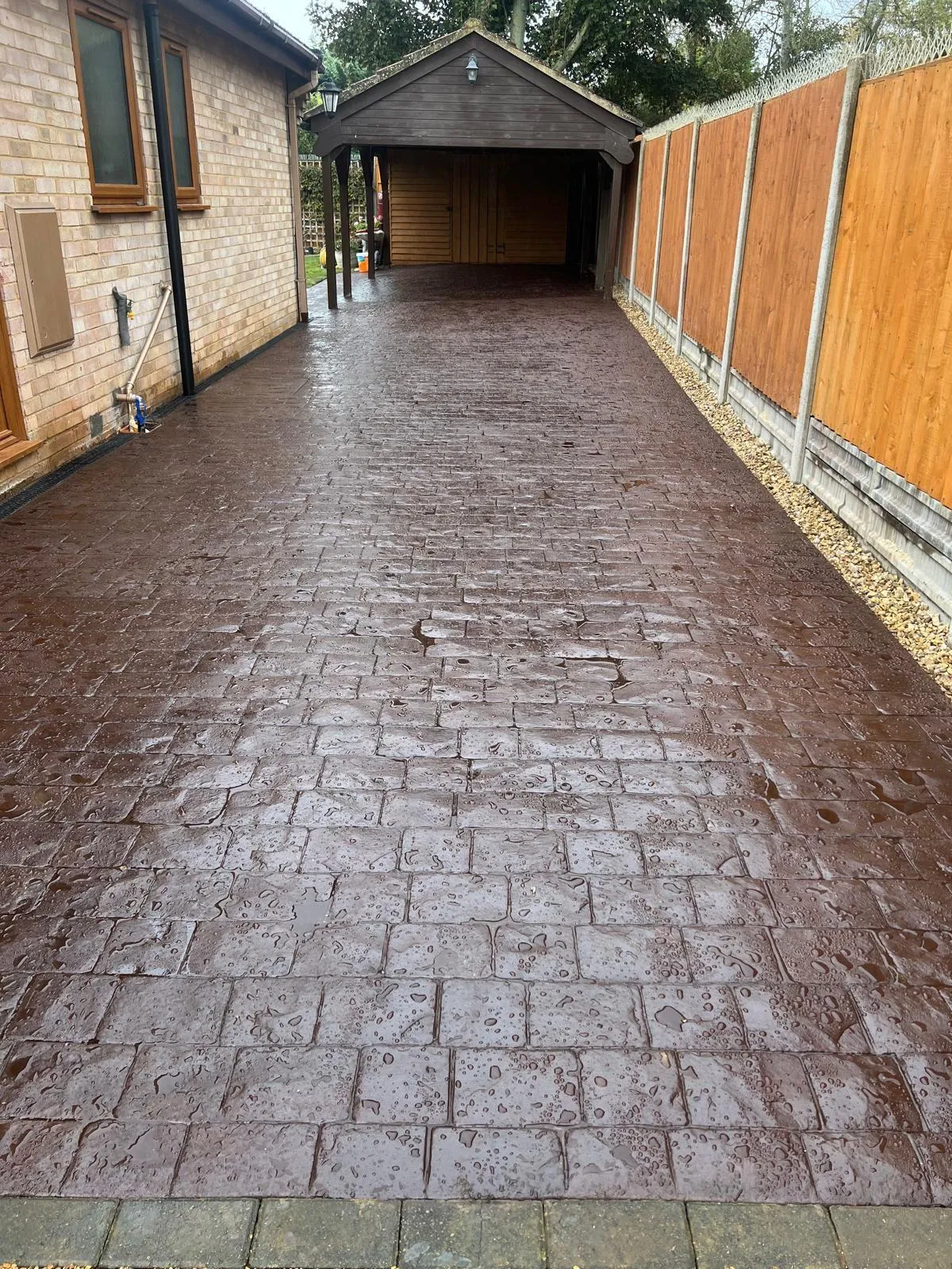Red cobble pattern imprinted concrete driveway, sealed to a wet-look finish